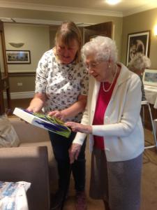 Cathey from Buxton Art Trail shows a resident from Haddon Hall Care Home a piece of artwork from the Trail contributed by artist Fiona Jubb.
