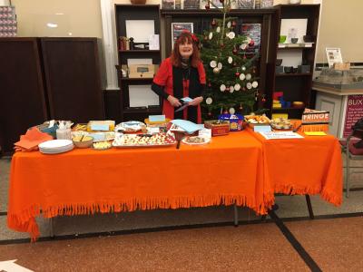 Committee member Catherine stands behind a table laden with festive treats. (JH)
